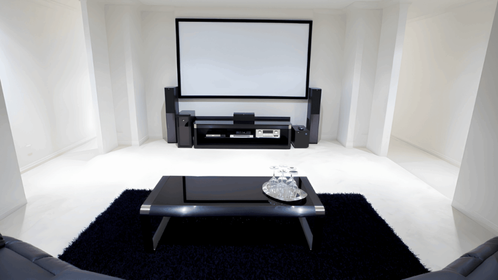 Modern home theater system setup in a living room with large screen, surround sound speakers, and comfortable seating for immersive entertainment.